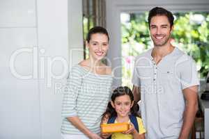 Portrait of smiling family with daughter holding lunch box