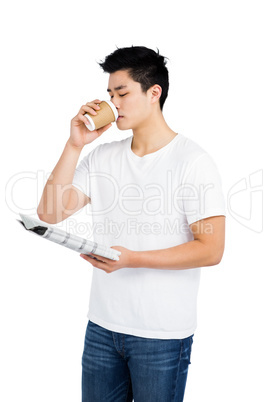 Young man having coffee and reading newspaper