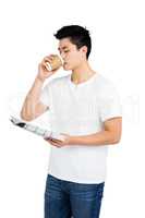 Young man having coffee and reading newspaper