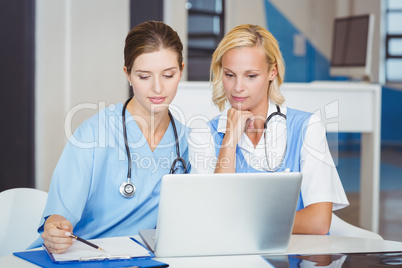 Female doctors using laptop while sitting at desk