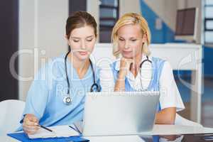 Female doctors using laptop while sitting at desk