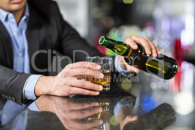 Businessman pouring whisky in glass