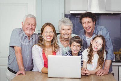 Portrait of smiling family with laptop in kitchen