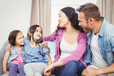 Happy parents sitting with daughters on sofa