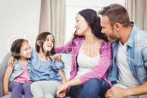 Happy parents sitting with daughters on sofa