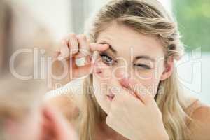 Young woman applying contact lens