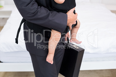 Midsection of father carrying baby with briefcase
