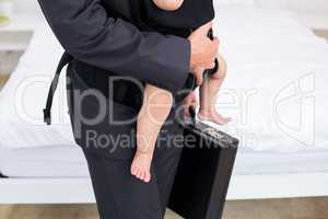 Midsection of father carrying baby with briefcase