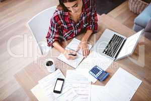 High angle view of woman writing in notepad