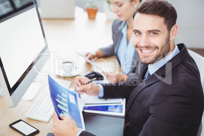 Happy businessman holding graph computer desk Happy businessman holding graph computer desk