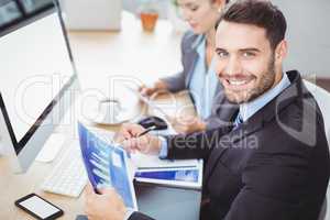 Happy businessman holding graph computer desk