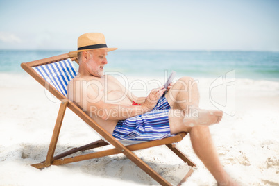 Senior man using tablet at the beach