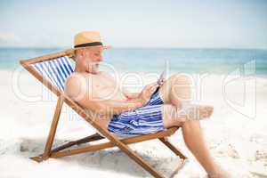 Senior man using tablet at the beach