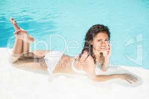 Portrait of beautiful woman lying by swimming pool