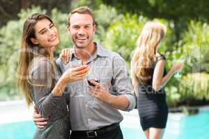 Couple drinking cocktail by swimming pool at party