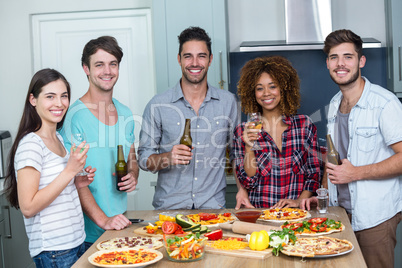 Happy multi-ethnic enjoying alcohol and pizza at table