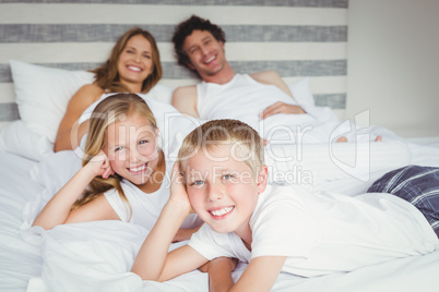 Portrait of happy family resting on bed