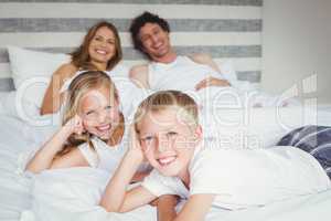 Portrait of happy family resting on bed