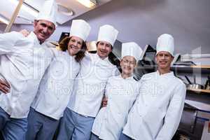 Happy chefs team standing together in commercial kitchen