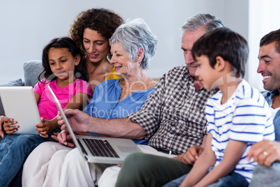 Happy family using laptop and digital tablet in living room