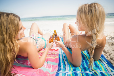 Women lying on the beach with beer bottle