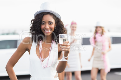 Happy friends drinking champagne in front of a limousine