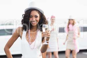 Happy friends drinking champagne in front of a limousine