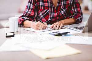 Midsection of woman writing in notepad