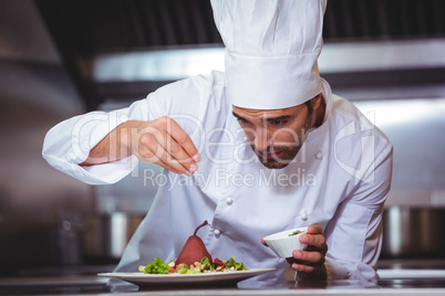 Chef sprinkling spices on dish