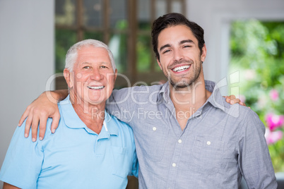 Portrait of smiling father and son with arm around