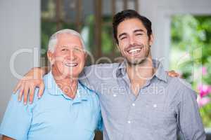 Portrait of smiling father and son with arm around