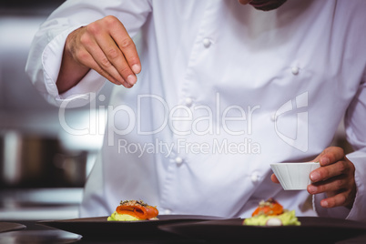 Chef sprinkling spices on dish