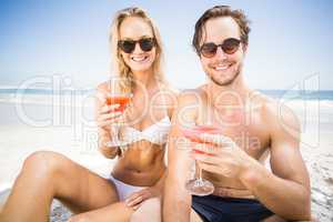 Portarit of young couple in sunglasses having cocktail on the be