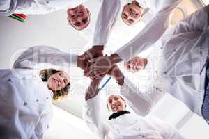 Portrait of chefs team putting hands together and cheering
