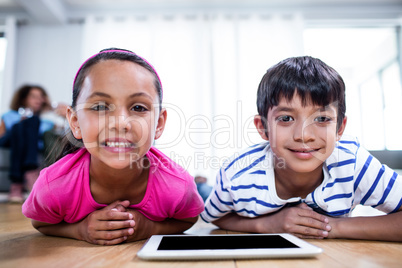 Portrait of brother and sister lying on floor with digital table Portrait of brother and sister lying on floor with digital table