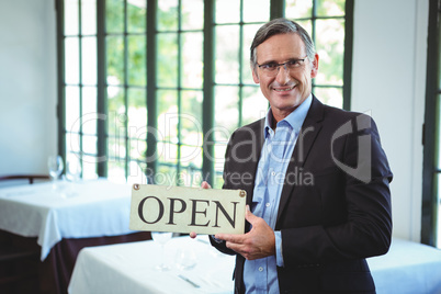 Smiling businessman holding open sign