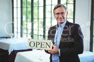 Smiling businessman holding open sign