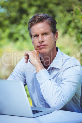 Thoughtful businessman using laptop with coffee