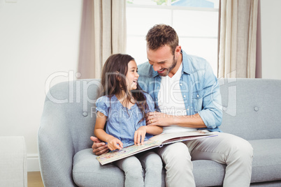 Happy father with daughter on sofa at home