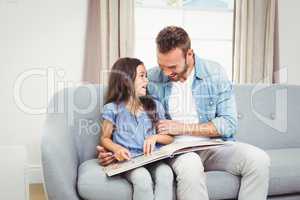 Happy father with daughter on sofa at home