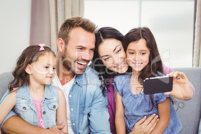 Family smiling while taking selfie on cellphone