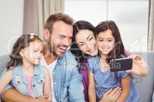 Family smiling while taking selfie on cellphone