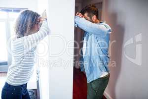 Couple leaning on opposite sides of the wall