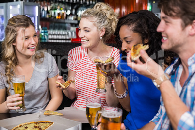 Happy friends having a drink and pizza