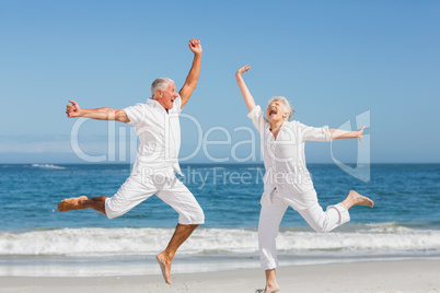 Senior couple jumping at the beach