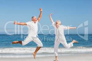 Senior couple jumping at the beach