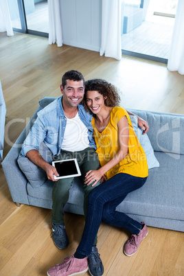 Portrait young couple sitting on sofa and using digital tablet