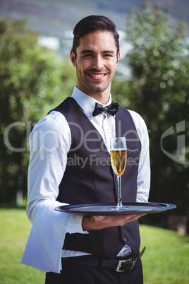 Handsome waiter holding a tray with glass of champagne