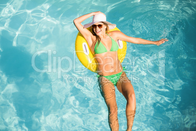 Happy woman in green bikini floating on inflatable tube in swimm