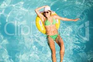 Happy woman in green bikini floating on inflatable tube in swimm